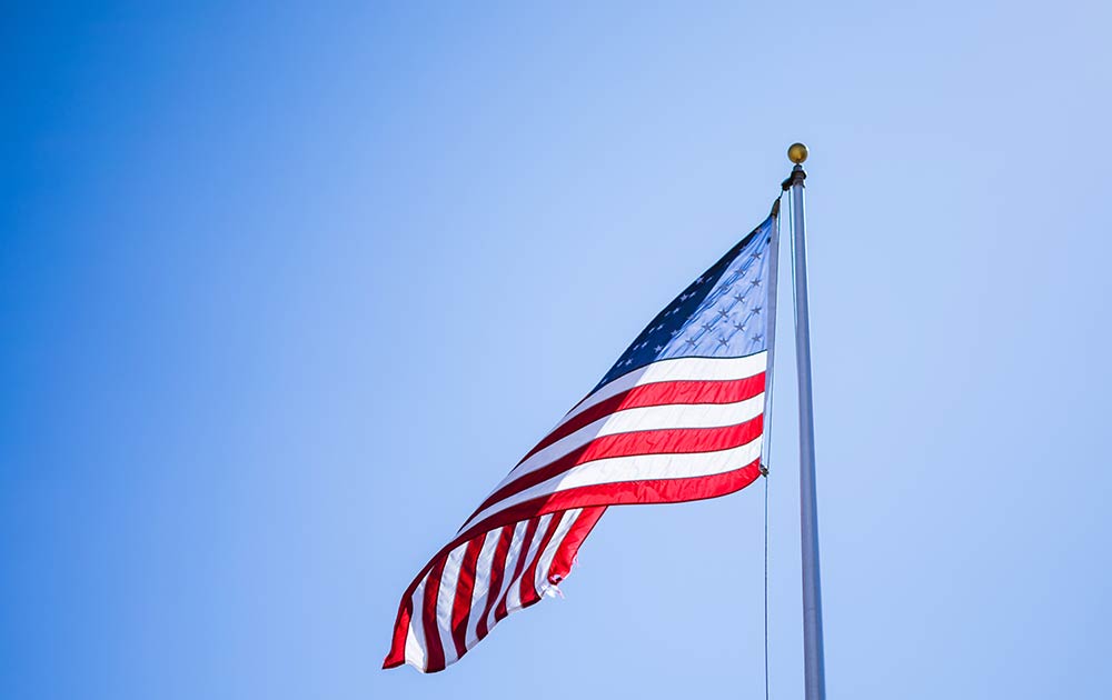 American Flag on flag pole against blue sky