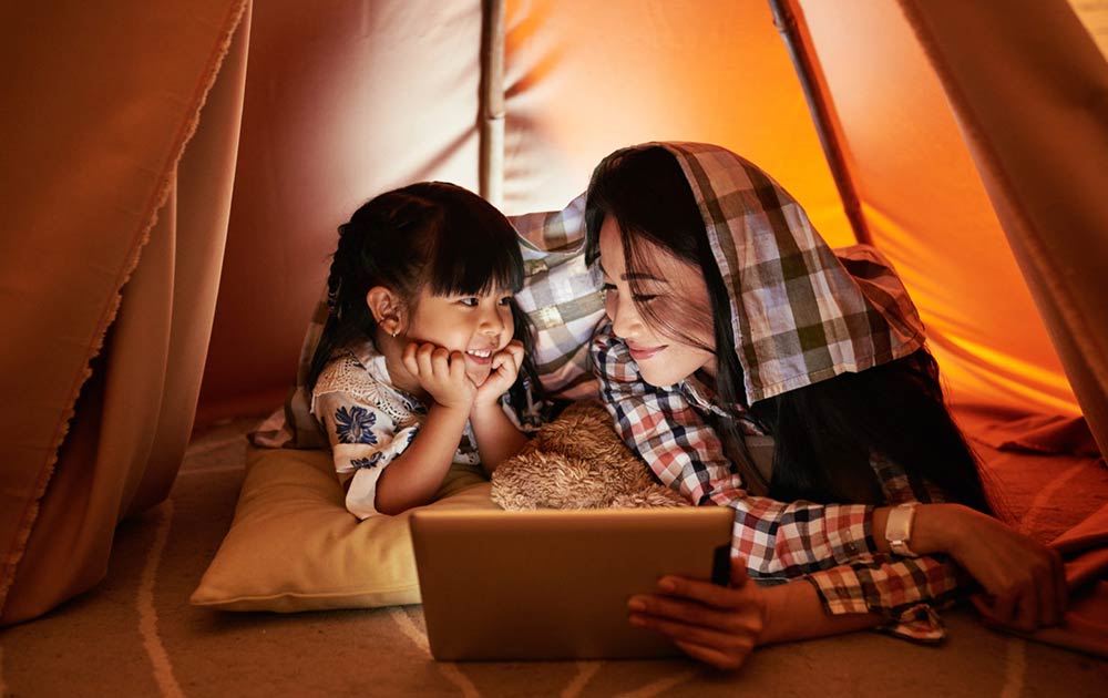 mom and daughter watching movie in tent