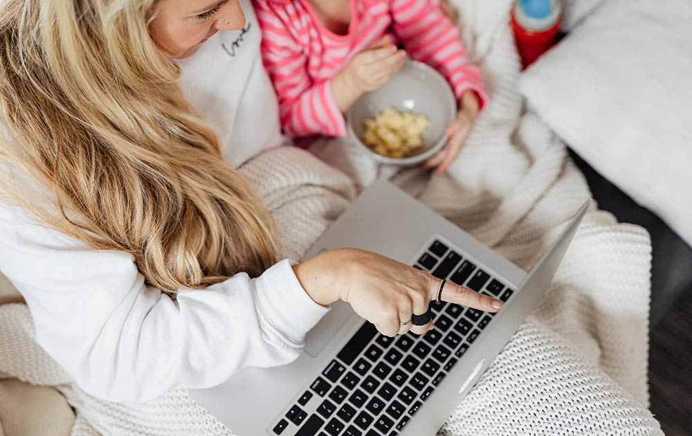 mom and daughter watching movie on laptop with popcorn